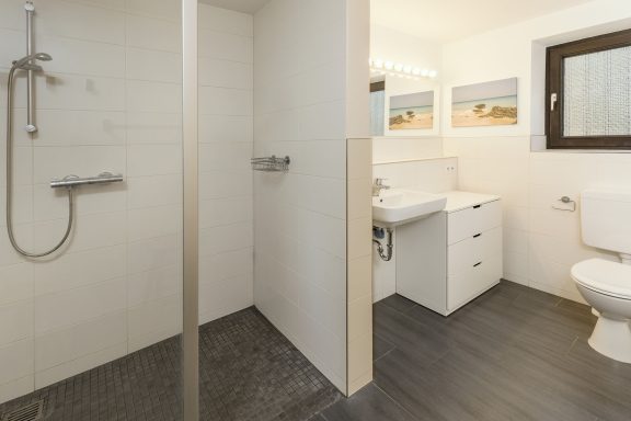 Modernes Badezimmer mit Dusche, Waschbecken und Toilette in neutralen Farbtönen.