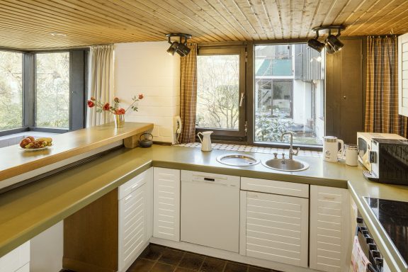 Helle, moderne Küche mit Fenster, Holzdecke und einfacher Ausstattung.