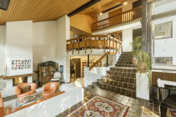 Helles Wohnzimmer mit Treppe, Holzdetails und stilvoller Einrichtung.